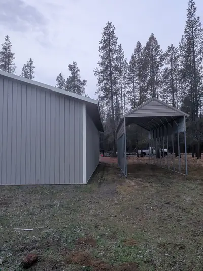 Enclosed steel building and carport side by side